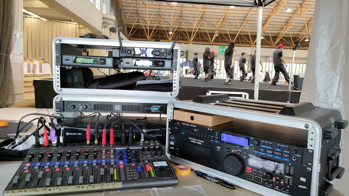 ステージの横に設置されたミキサーやアンプなどの音響機器。滋賀県愛荘町の福祉センターラポール秦荘はつらつドーム にて株式会社大兼工務店様主催の「第25回だいかね祭り」が開催され、ステージイベントの音響業務を担当させていただきました。
